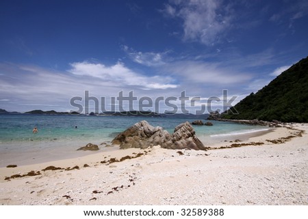Rocks on turquoise blue tropical beach under sunny sky in Okinawa, Japan
