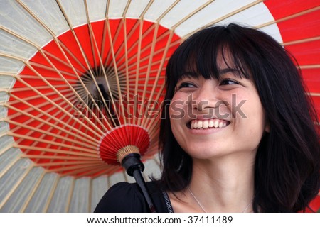 Beautiful Japanese girl laughing while holding a Japanese rice paper umbrella