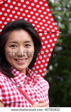 Beautiful Chinese girl with dotted umbrella and shirt smiling