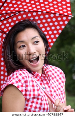 Beautiful Chinese girl with dotted umbrella and shirt surprised