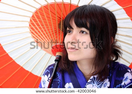 Young Japanese beauty dressed in kimono posing with a traditional umbrella