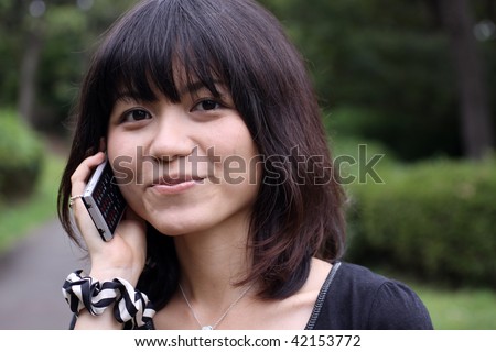 Beautiful young Japanese girl with cellphone smiling shy