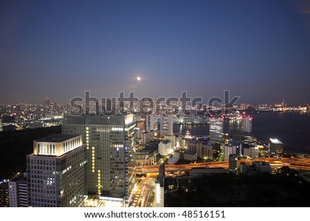 Full moon shining over illuminated buildings in the Tokyo bay
