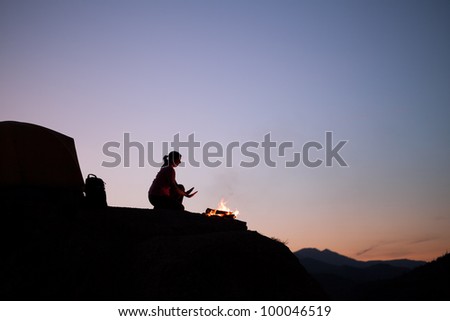 Silhouette of Female Camper Staying Warm by the Campfire