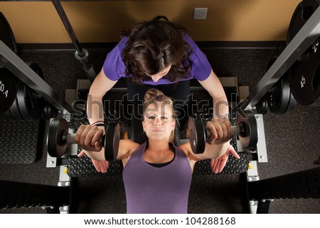 Young Woman Lifting Weights with Personal Trainer
