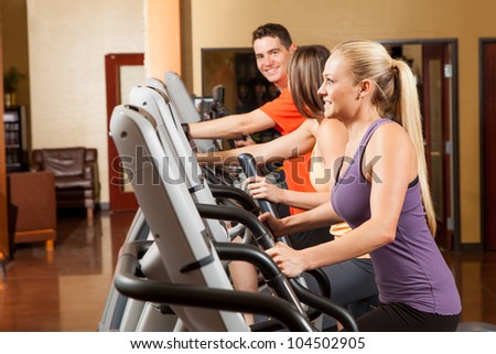 Three People Exercising on Elliptical Trainers at Fitness Center