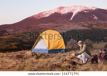 Young Man Camping and Keeping Warm by Fire