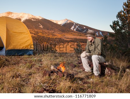 Young Man Camping and Sitting Next to Fire