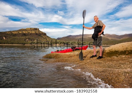 Young at Heart.  Senior Man Surveying the Lake Before a Paddle. A Rolling Wave Outlines the Shore.