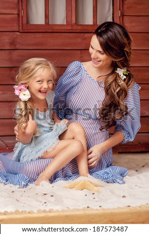 portrait of pregnant woman, ukrainian style,  blue dress, with daughter, smiling, hugging