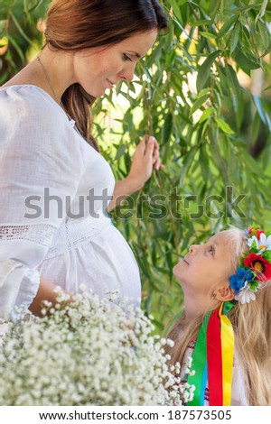 portrait of pregnant woman, ukrainian style, white, pink dress, with daughter, with flowers,