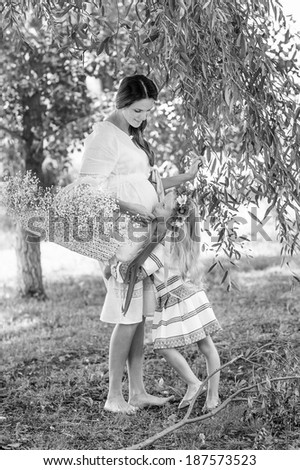 white and black portrait of pregnant woman, ukrainian style, white, pink dress, with daughter, with flowers,