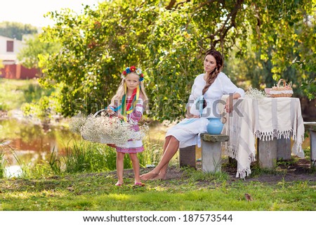 portrait of pregnant woman, ukrainian style, white, pink dress, with daughter, with flowers, milk, table