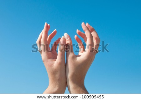 Woman hands cupped with fingers out against a blue sky like she is about to receive something