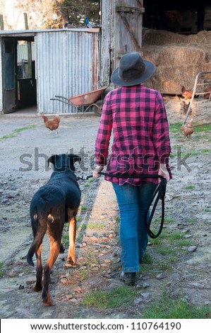 Young farm girl and dog going to feed chickens
