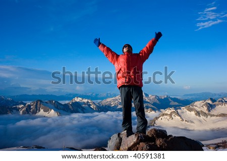 Rock-climber on background mountain landscape with the hands stretched in sides