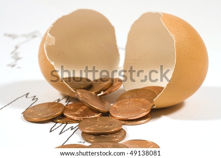 Broken egg with pennies. Shallow depth of field with focus on coins in front.