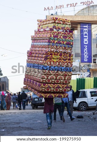 ADDIS ABABA. ETHIOPIA - DECEMBER 21, 2013: Man carries pile of foam mattresses in Merkato market. Merkato market is the largest open air market in Africa.