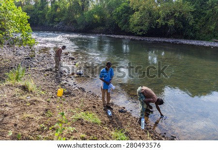 MAGO NATIONAL PARK, OMO VALLEY, ETHIOPIA - JANUARY 01, 2014: People draw water from the Mago River to bottles. Water is a treasure in Africa.
