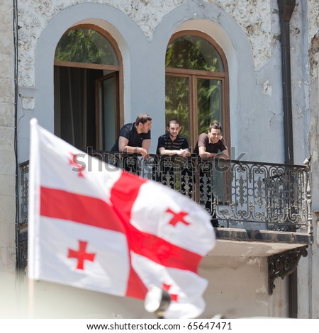 TBILISI - MAY 26: The Independence Day of Georgia. Young men watch military parade from old building balcony. May 26, 2010 in Tbilisi, Georgia.