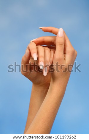 close-ups of the hands of a young woman with long white nails nail against a blue background