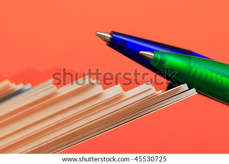 Pen and paper ordered on a colored background