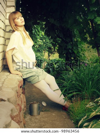 pregnant woman in profile, sitting in the garden