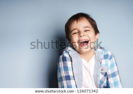 Portrait Of Happy Joyful Laughing Beautiful Little Boy On Blue Background