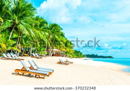 Beach chairs on the white sand beach with cloudy blue sky and su