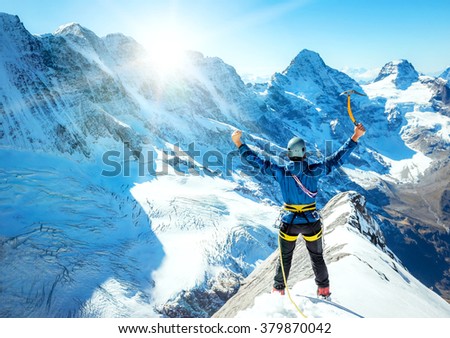 Mountaineer reaches the top of a snowy mountain. Extreme sport concept