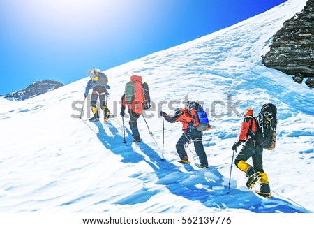 Group of climbers reaches the top of mountain peak. Climbing and mountaineering sport. Teamwork concept.
