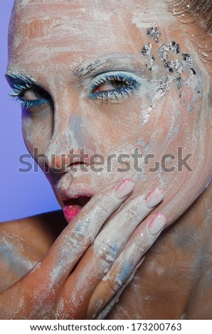 Young beautiful woman on the face smears colored paint