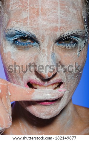 Young woman with paint on his face biting her finger