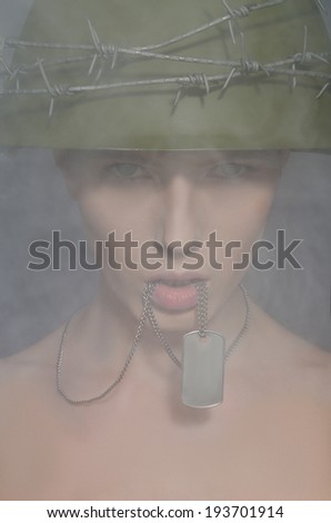 Portrait of woman in army helmet with a coin in his mouth