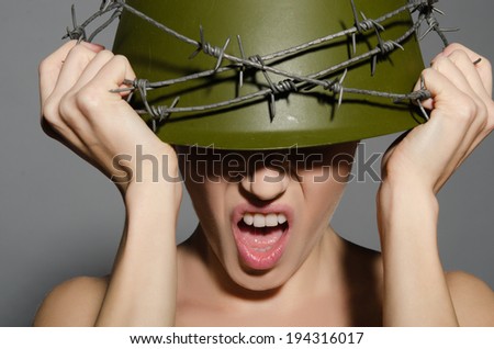 Woman in army helmet with barbed wire isolated on gray