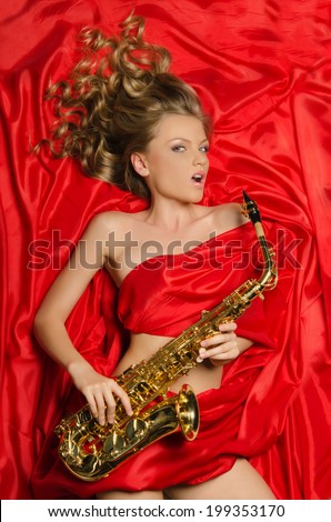 Young woman with a golden saxophone isolated on red