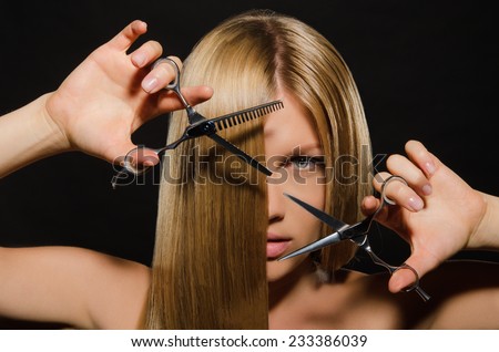 Young beautiful woman with straight hair and scissors on black background