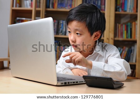 Asian school boy in white shirt pointing to computer screen