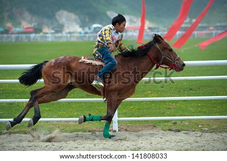 ZHONGDIAN - JUNE 11: participant races during the Shangrila horse racing festival on June 11, 2013 in Zhongdian, China. This festival is the most important horse racing festival in Southwest China.