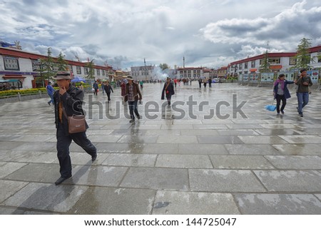 LHASA - JUNE 5: Unidentified Tibetan devotees walk on the Barkhor area on June 5, 2013 in Lhasa, Tibet. The Barkhor area is the site of the Jokhang Temple, Tibet\'s holiest temple.