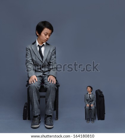 Big boy & small case, small boy & big case in business suit (uniform) sitting on chair (future career concept)