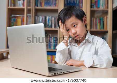 Asian boy looking frustrated in front of laptop computer