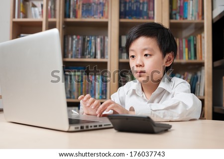 Smart Asian schoolboy wearing white shirt working on computer