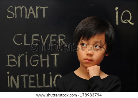 Smart looking Asian boy against black background (blackboard with text)