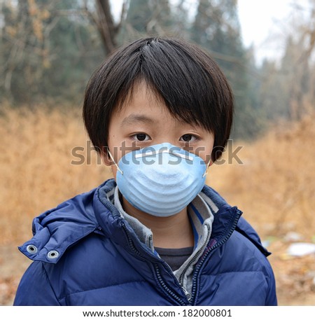 Asian boy wearing mouth mask standing in front of dry forest affected by pollution