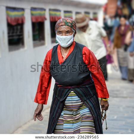KATHMANDU - OCTOBER 16: Tibetan woman circles the Boudha temple on October 16, 2014 in Kathmandu, Nepal. Devotees from all over the world visit this site for religious merit and good luck.