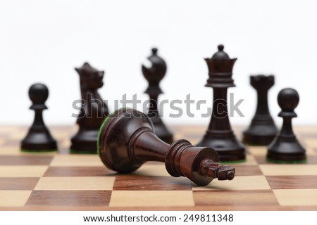 Concept of defeat (fallen king, camera focus on black king chess piece, background blurred)