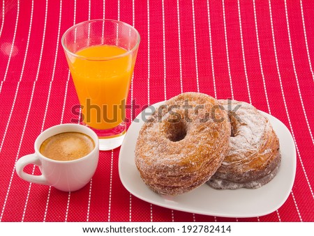 Half-donut and half-croissant pastries, orange juice and coffee.