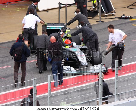 BARCELONA - FEBRUARY 28: Mechanics push Michael Schumacher\'s car into the pit during Formula One Teams Test Days at Catalunya circuit February 28, 2010 in Barcelona.