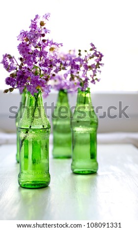 purple flowers in green bottles